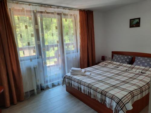 - une chambre avec un lit doté d'une couverture et de fenêtres dans l'établissement Casa Maia, à Cârţişoara
