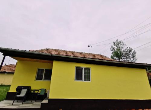 una casa amarilla con sillas delante en Casa Rusu en Mălăeşti