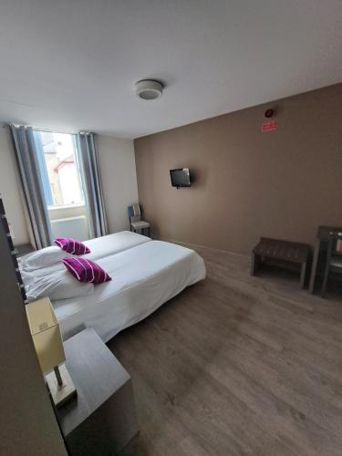 um quarto de hotel com uma cama grande com almofadas roxas em Hotel de la poste em Tardets-Sorholus