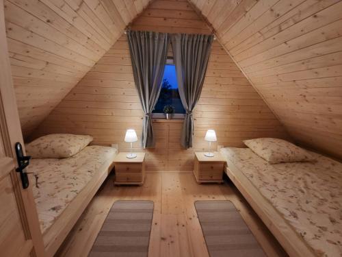 an attic bedroom with two beds and two lamps at Leśna Zagroda - Dominikowo - Tężnia, sauna, balia in Dominikowo
