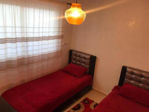 ein Schlafzimmer mit einem Bett mit einer roten Decke und einem Fenster in der Unterkunft اقامة السعادة in Nador