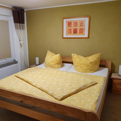 a bedroom with a bed with yellow sheets and pillows at Ferienhaus Willkommen in Bad Schandau