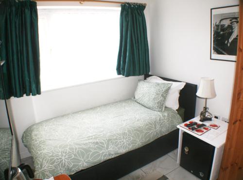 a small bedroom with a bed and a window at Woodside Lodge in Thurstaston