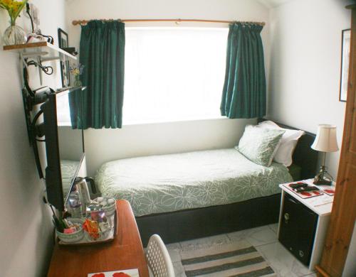 niewielka sypialnia z łóżkiem i oknem w obiekcie Woodside Lodge w mieście Thurstaston