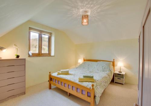 a bedroom with a bed and a dresser and a window at Tyn y Maes in Bethesda