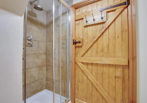 a bathroom with a shower and a wooden door at Tyn y Maes in Bethesda