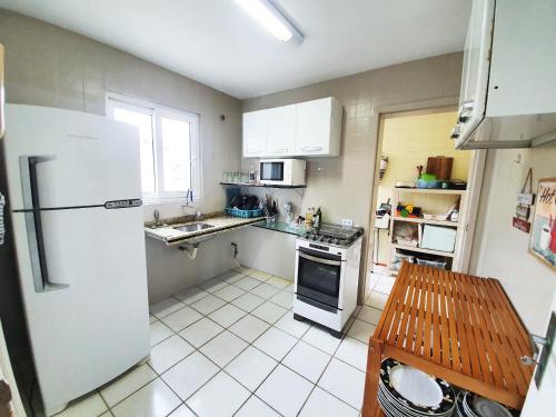 uma cozinha com um frigorífico branco e um lavatório em Apt com vista para o mar e churrasqueira em Guaratuba