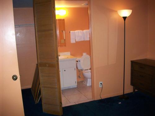 a bathroom with a toilet and a sink and a lamp at All-Suite Motel, LLC in Edgewater