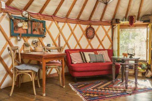 Habitación con sofá rojo y mesa en una yurta en The Yurt in Abirim, en Abirim