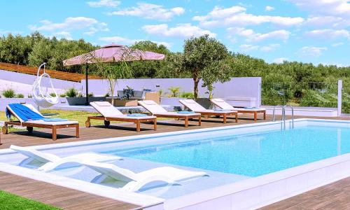 a swimming pool with lounge chairs and an umbrella at Stavento Luxury Villa Private Pool in Georgioupolis