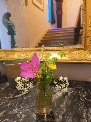 un vase avec des fleurs sur une table devant un miroir dans l'établissement Maison De l'Aguze, à Saint-Pons