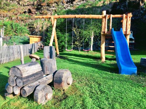 a playground with a blue slide and a wooden play structure at Feichterhof in Riva di Tures