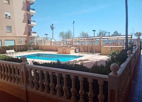 una recinzione intorno alla piscina di fronte a un edificio di FUENGIROLA ESTUDIO PLAYA PERLA 2 a Fuengirola