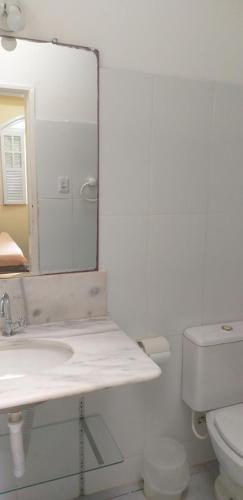uma casa de banho branca com um lavatório e um espelho em A Bela Casa da Ilha, na Ilha de Vera Cruz, Coroa, 300m da praia! em Salvador