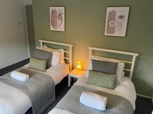 a room with two beds and a table with a lamp at Montrose - Perfect Contractor Stay Own Driveway 3 bedrooms in Gateshead