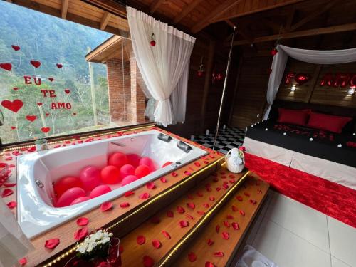 a room with a tub filled with red balls at Cabana Dois Amores. Destino romântico. in Barracão