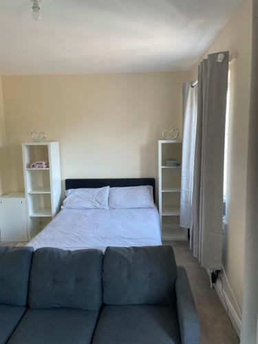 a bed with a blue couch in a bedroom at Private Rooms In A Cheerful 4-Bedroom Town House in Broughton