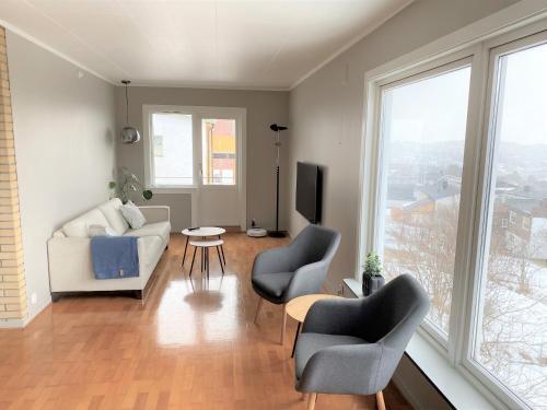 uma sala de estar com um sofá, cadeiras e janelas em Big central house, free parking, wifi, 3 bedrooms em Narvik