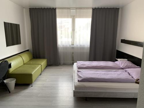 a bedroom with a bed and a couch and a window at City Hotel Dinslaken in Dinslaken
