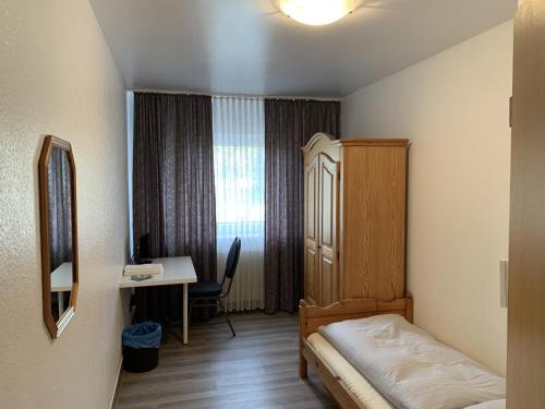 a small room with a bed and a desk and a table at City Hotel Dinslaken in Dinslaken