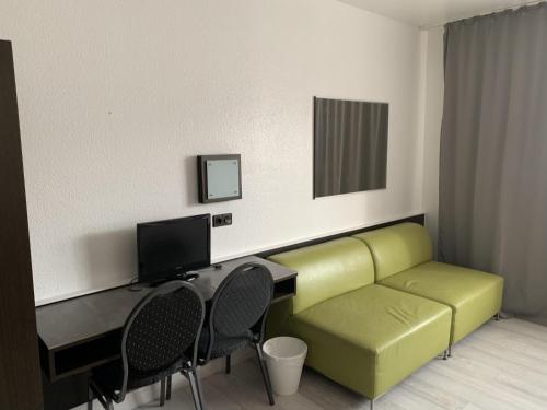 ein Wohnzimmer mit einem Sofa und einem Schreibtisch mit einem Computer in der Unterkunft City Hotel Dinslaken in Dinslaken
