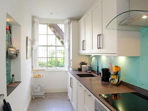 a kitchen with white cabinets and a sink and a window at Seashore Apartment in Sandgate