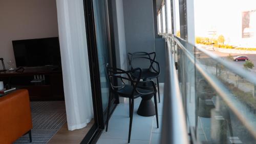 a room with a balcony with two chairs and a television at Luxury Apartment at Ellipse Waterfall, Midrand Near Mall of Africa in Midrand