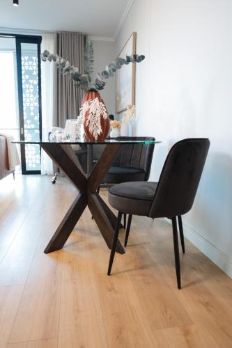a glass dining table with a black chair in a room at Luxury Apartment at Ellipse Waterfall, Midrand Near Mall of Africa in Midrand
