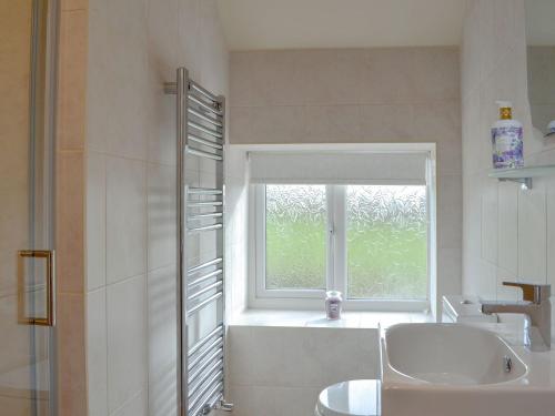 a bathroom with a window and a sink and a bath tub at Besss Cottage in Middlewich