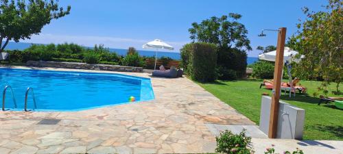 a swimming pool in a yard with an umbrella at Viena Rooms & Apartments in Palaiochóra