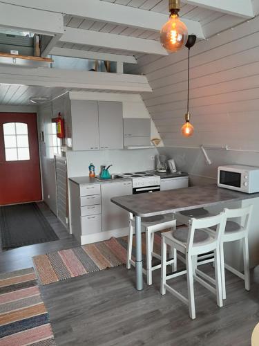 eine Küche mit einem Tisch und einigen weißen Schränken in der Unterkunft Karemajat superb cottage in Ylitornio
