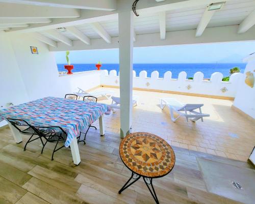 a room with a table and chairs and the ocean at Seafront House Gabbiano Azzurro in Santa Flavia