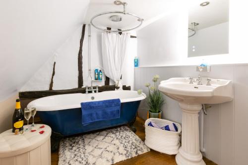 a bathroom with a blue tub and a sink at Vine Cottage 