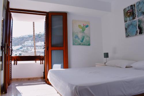 1 dormitorio con cama blanca y ventana en Bungalow Guayana en Mogán