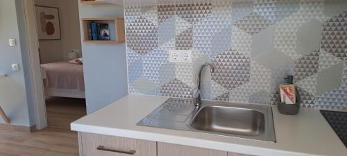 uma cozinha com um lavatório e uma parede com azulejos em Viena Rooms & Apartments em Palaiochora
