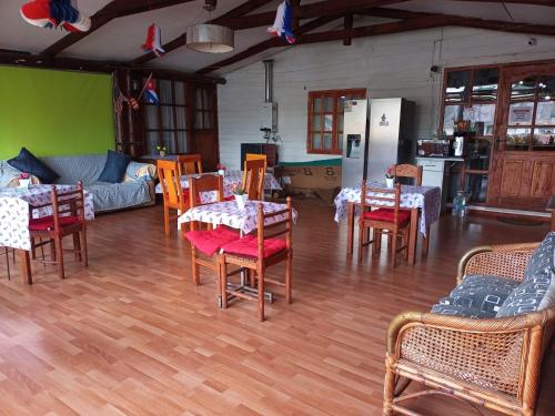 a living room with tables and chairs and a kitchen at Hostal Valentino in Villarrica