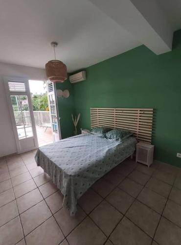 a bedroom with a bed in a green wall at Bas de villa spacieux, proche plages et centre in Schœlcher