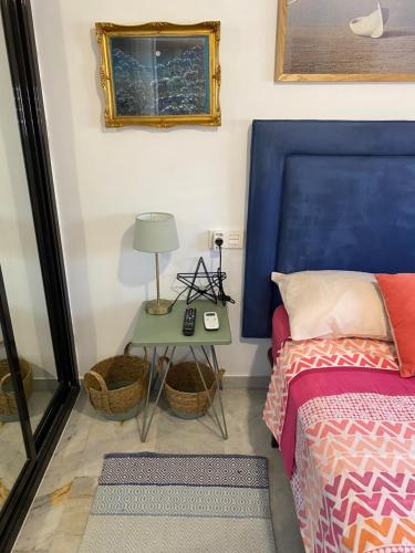 アルムニェーカルにあるApartamento con vistas en Marioteのベッドルーム1室(青いヘッドボードとテーブル付きのベッド1台付)