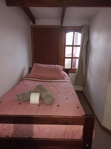 a bedroom with a bed with a pink comforter and a window at Hostal Valentino in Villarrica