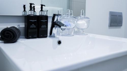 a counter with a sink with glass bottles on it at Luxury Apartment at Ellipse Waterfall, Midrand Near Mall of Africa in Midrand