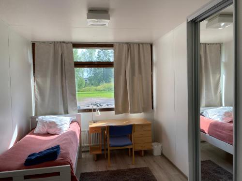 Habitación con 2 camas, escritorio y ventana. en Kokemäen opisto, en Kokemäki