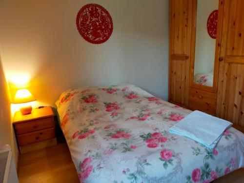 1 dormitorio con 1 cama con colcha de flores y mesita de noche en a nice room en Annemasse