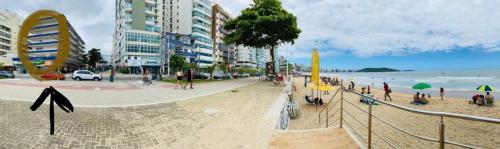 een strand met een groep mensen op het strand bij Suíte Mar Econômica e Compacta - Praia do Morro - Prédio frente Mar com elevador, atravessou a avenida, já está na Praia - Garagem - Internet in Guarapari