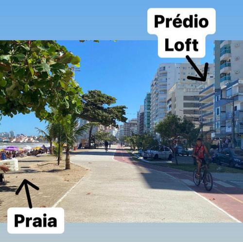 a person riding a bike down a city street at Suíte Mar Econômica e Compacta - Praia do Morro - Prédio frente Mar com elevador, atravessou a avenida, já está na Praia - Garagem - Internet in Guarapari
