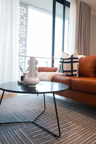 a living room with a couch and a table at Luxury Apartment at Ellipse Waterfall, Midrand Near Mall of Africa in Midrand
