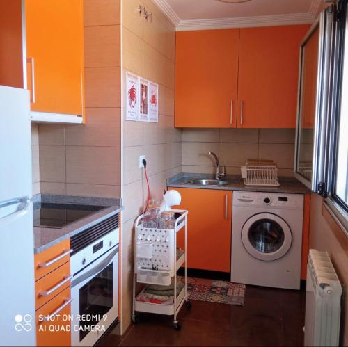 a kitchen with orange cabinets and a washing machine at El Pisito de Baiona in Baiona
