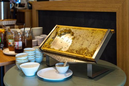 Ein Bienenstock auf einem Tisch mit Tassen und Tellern in der Unterkunft Hôtel Restaurant la Corniche in Bastia
