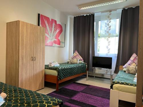 Zimmer mit 2 Betten, einem Schrank und einem TV in der Unterkunft Ferienwohnung Mainz Bahnhof in Mainz