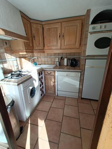 une cuisine avec des appareils électroménagers blancs et des armoires en bois dans l'établissement Appartement privatisé dans maison, à Utelle