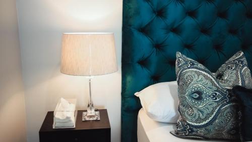 a bed with a pillow and a lamp on a night stand at Luxury Apartment at Ellipse Waterfall, Midrand Near Mall of Africa in Midrand